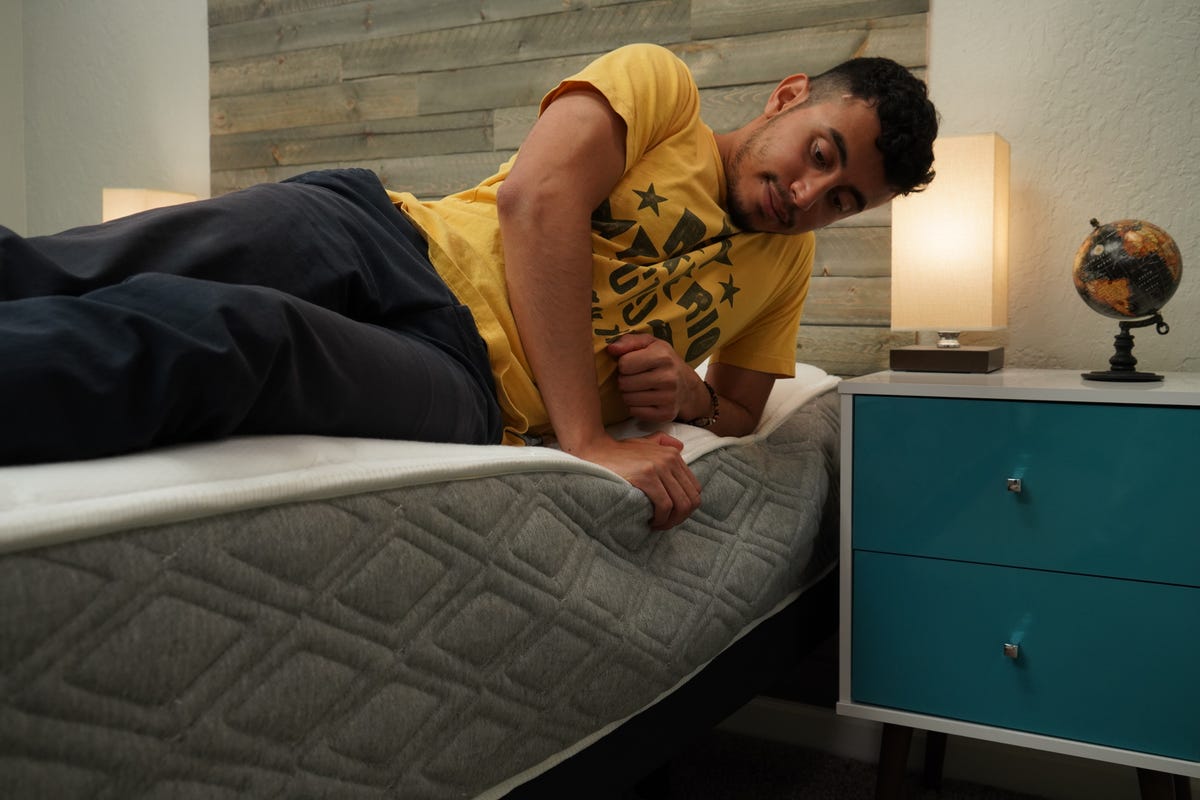 CNET staff member testing the edge support of the Allswell Luxe mattress.